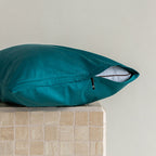 Pillow and teal pillowcase with invisible zipper on a textured surface with a neutral background.