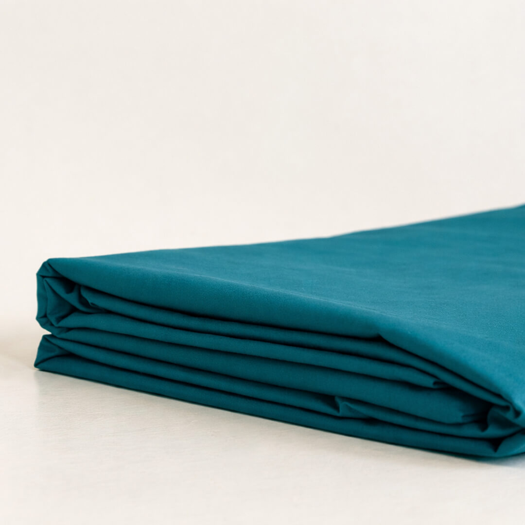 Folded teal fabric on a white background.