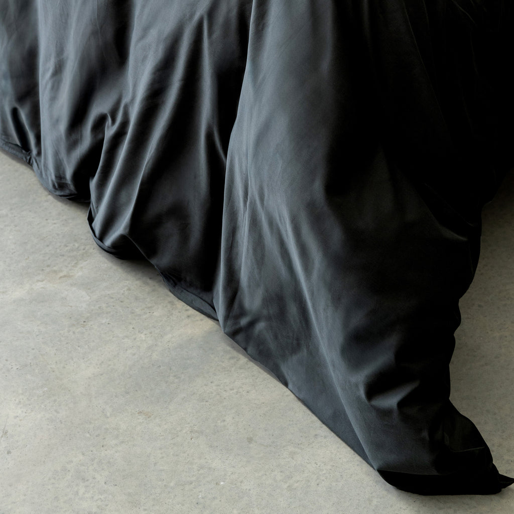 BLACK comforter on a bed with a light background