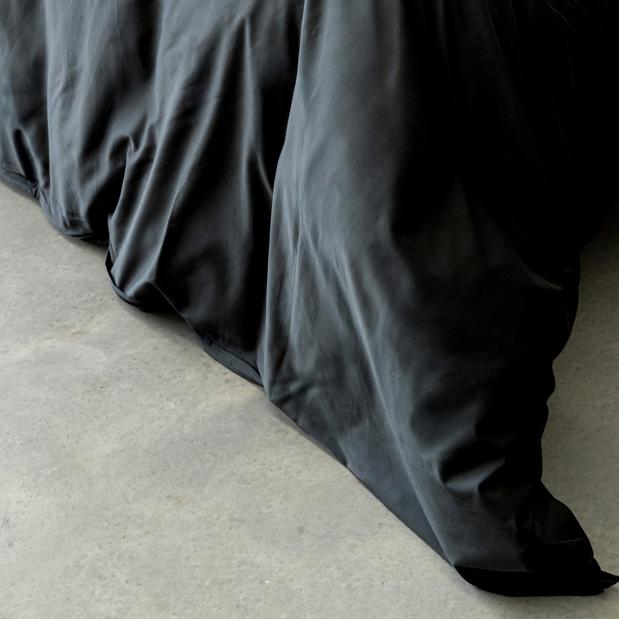 BLACK comforter on a bed with a light background