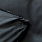 Close-up of a dark fabric with a magnet pocket detail on a matching background