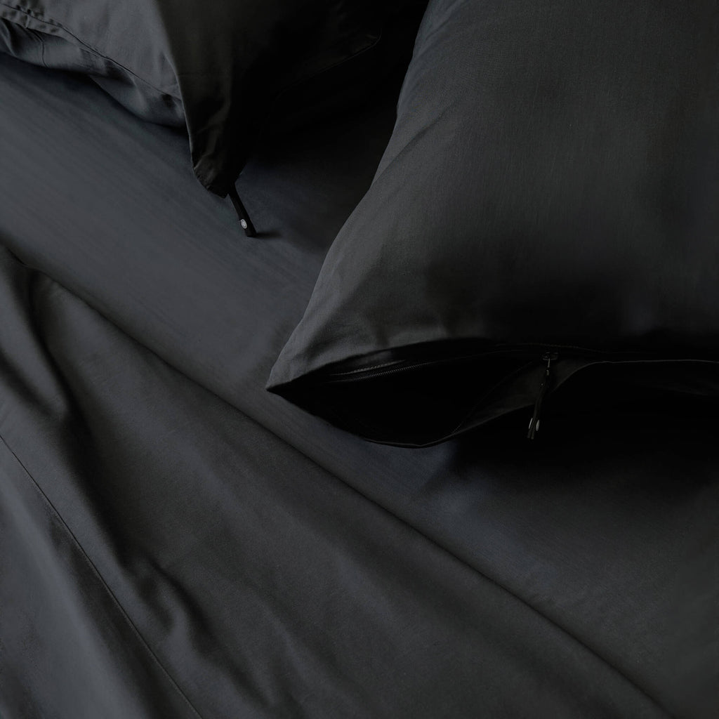 Close-up of dark gray bedding with a pillow on a bed.