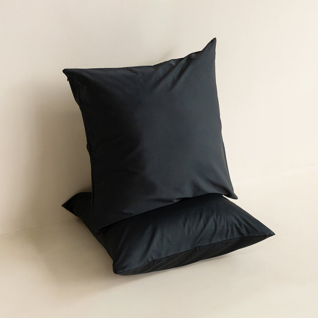 Two black pillows on a beige background.