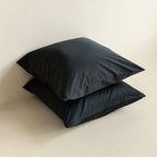 Two black pillows on a beige surface.