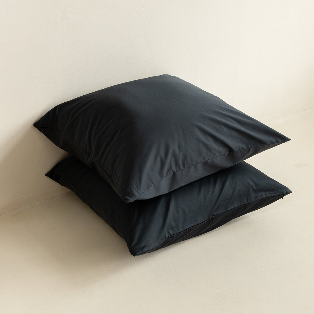 Two black pillows on a beige surface.