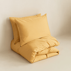 Neatly folded golden yellow quilt cover with two matching pillowcases stacked behind it