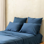 Blue bedding set with pillows on a bed against a beige wall.