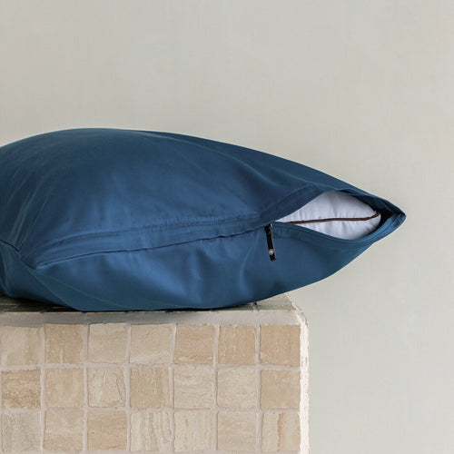 Pillow with a blue pillowcase, showcasing the invisible zipper half done up. 