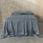 Striped bedspread and pillows on a bed against a textured wall.
