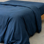 Navy blue quilt cover on bed, with neutral background. 