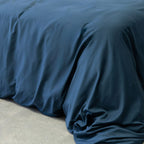 Navy blue quilt cover on bed, with neutral background. 