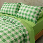 Meadow green gingham print quilt cover set on a bed, against a neutral concrete look backdrop.