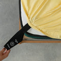 Close-up of a yellow fitted sheet with labelled corner loop strap being pulled onto mattress.