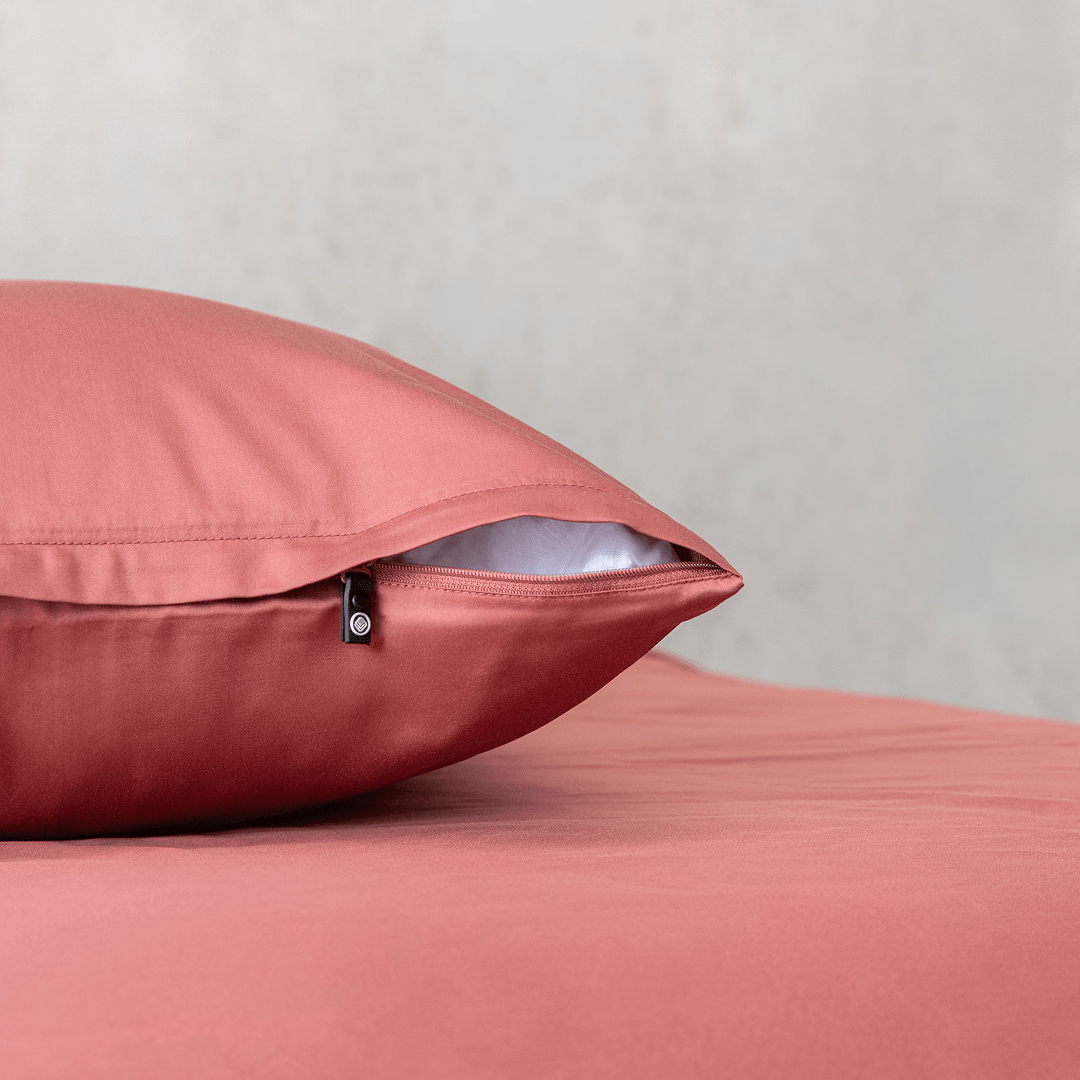 Close-up of a dusty rose pink pillowcase showing a partially open zipper closure revealing white pillow fill