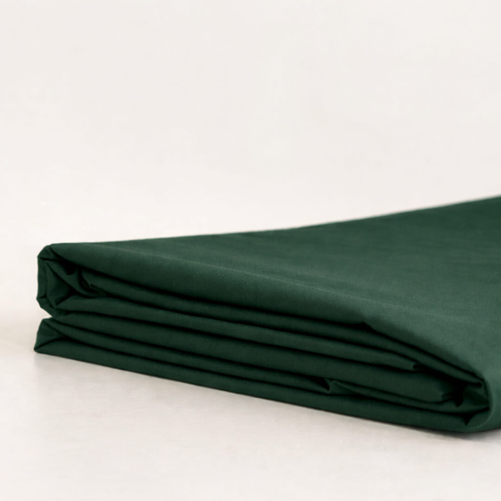 Folded forest green fabric on a light beige background.