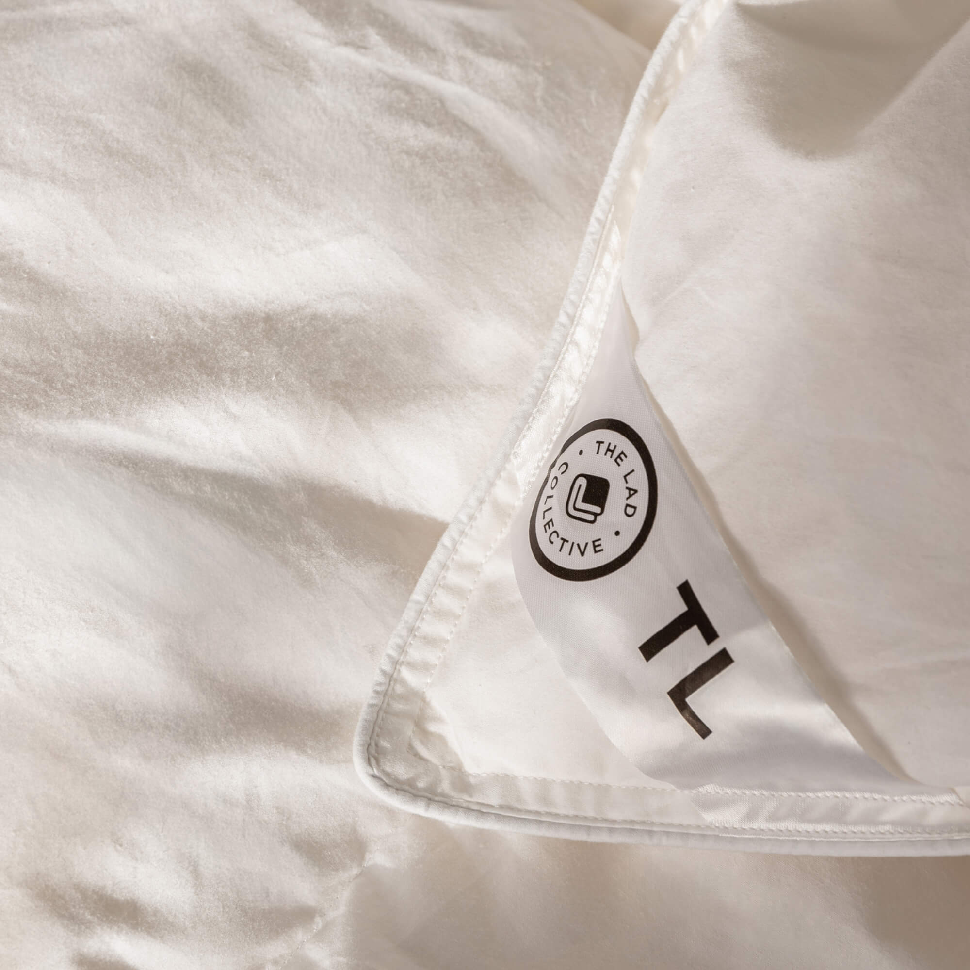 Close-up of a white comforter with a brand label on a quilt insert corner.