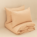 Neatly folded peach quilt cover with two matching pillowcases stacked behind it