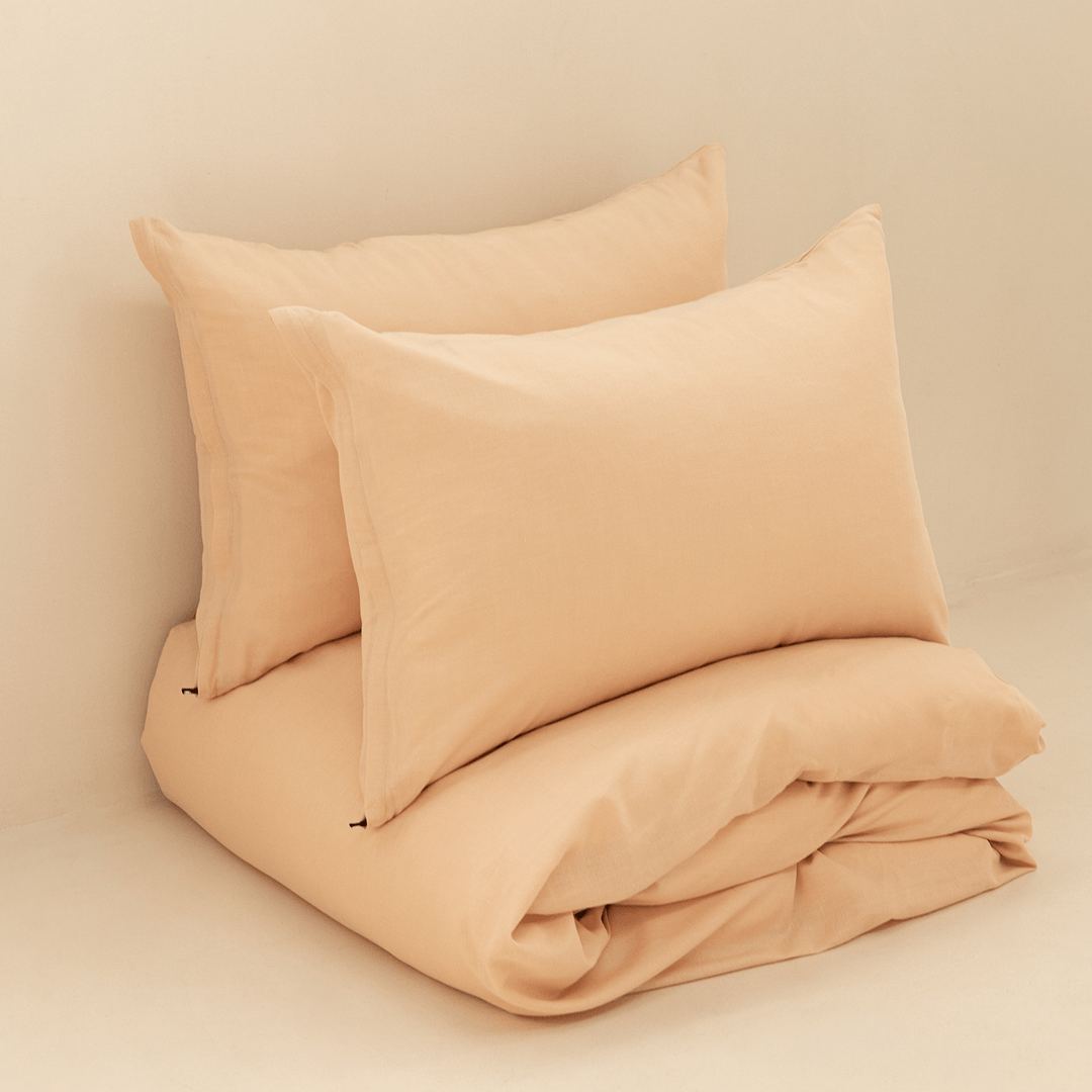 Neatly folded peach quilt cover with two matching pillowcases stacked behind it