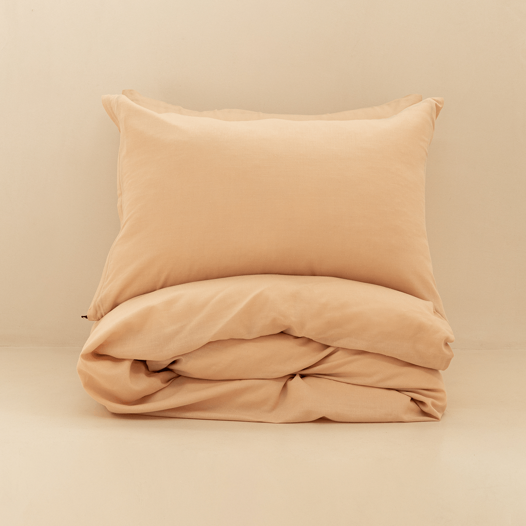 Neatly folded peach quilt cover with one matching pillowcase resting on top