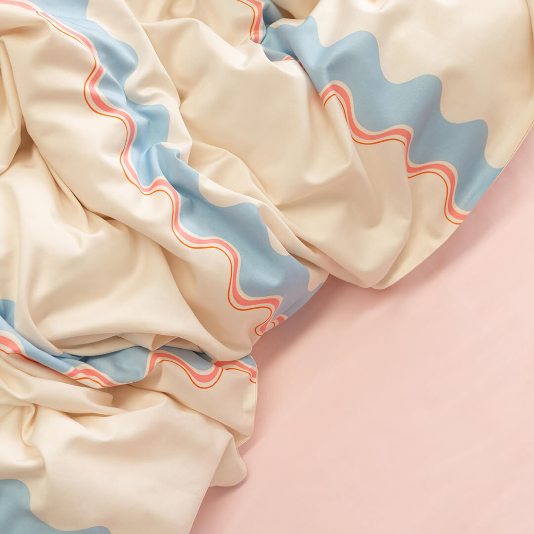 Close-up of a fabric with wavy blue and red lines on a pink background.