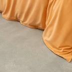 Close-up view of a mustard yellow quilt cover draping onto a light gray concrete floor