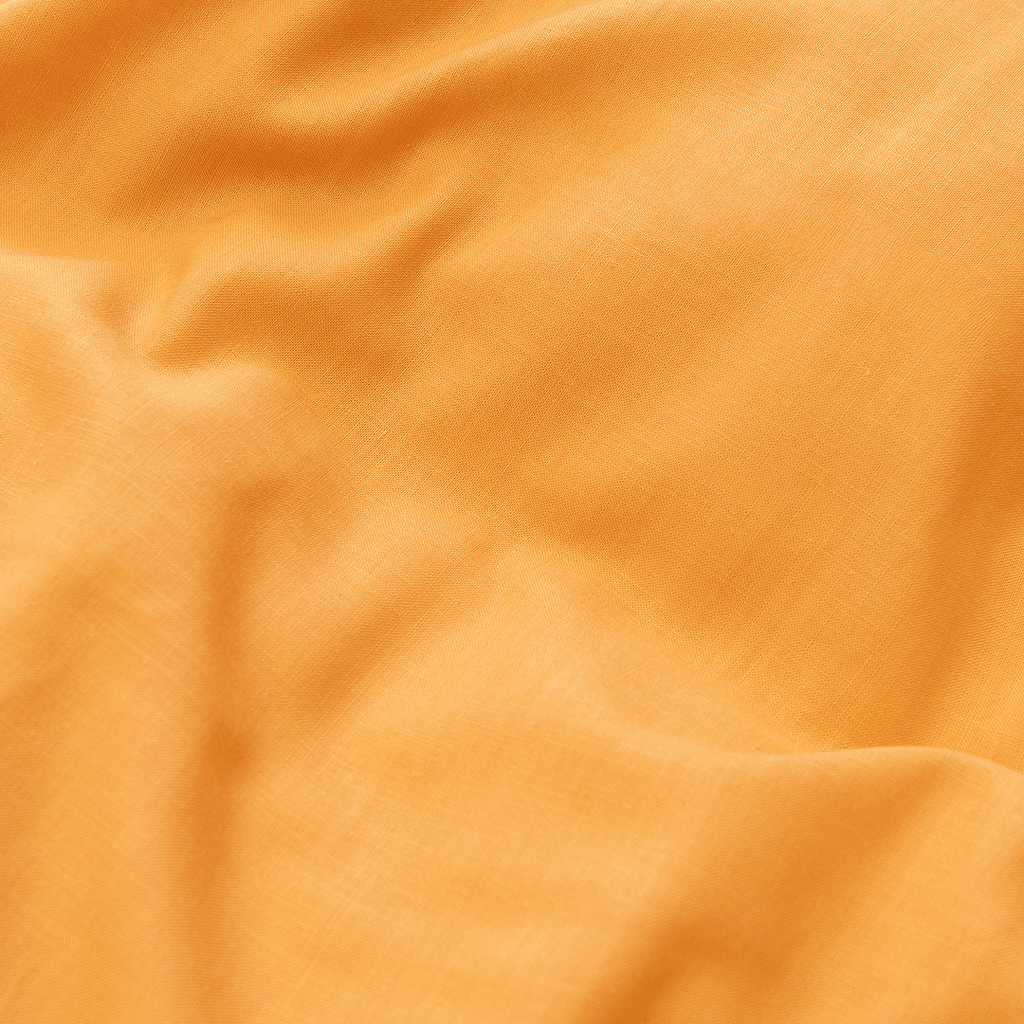 Extreme close-up showing the smooth texture and subtle weave of mustard yellow cotton fabric