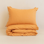 Neatly folded mustard yellow quilt cover with one matching pillowcase resting on top