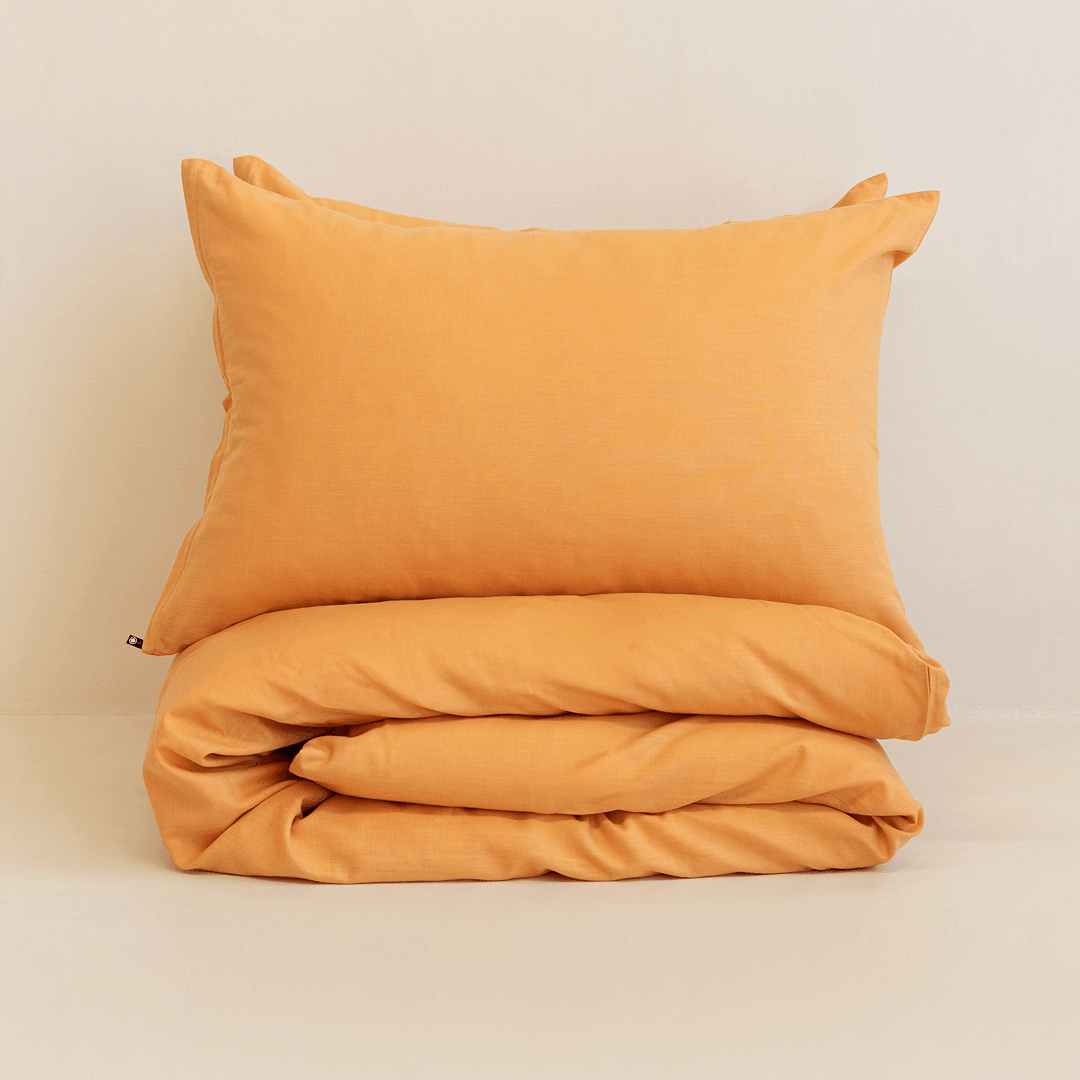 Neatly folded mustard yellow quilt cover with one matching pillowcase resting on top