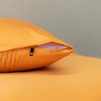 Close-up of a mustard yellow pillowcase showing a partially open zipper closure revealing white pillow fill