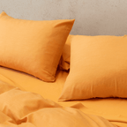 Close-up angle view of mustard yellow pillowcases resting on a matching flat sheet