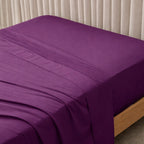 Purple bed sheets on a bed with a neutral background.