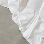 Close-up of a white lightweight quilt insert on a grey surface.