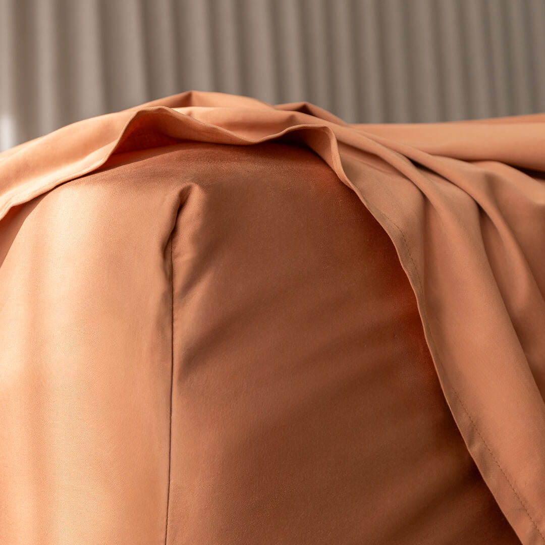 Close-up of a brown fabric fitted sheet corner with a neutral background.