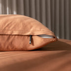 Brown pillow with a zipper on a matching brown surface.