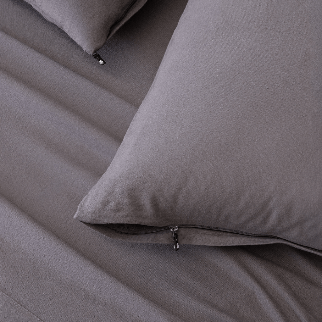 Close-up of charcoal grey pillowcases with concealed zipper closures, showcasing the secure fastening detail and soft brushed fabric texture.