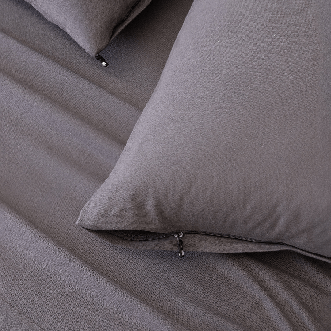 Close-up of charcoal grey pillowcases with concealed zipper closures, showcasing the secure fastening detail and soft brushed fabric texture.