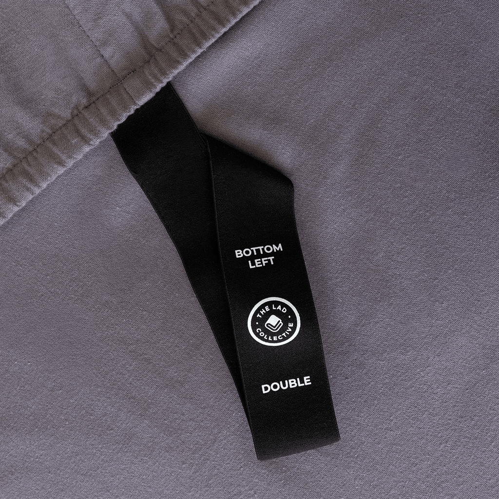 Close-up of a fitted sheet orientation tag labeled “Bottom Left,” designed to simplify bed-making and ensure correct sheet placement.
