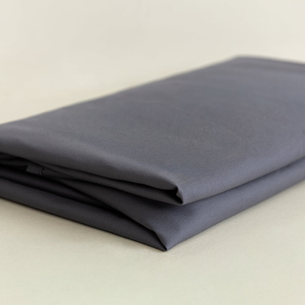 Folded dark grey fabric on a beige background.