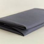 Folded dark grey fabric on a beige background.