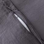 Close-up of a concealed zipper opening on a dark stone gray quilt cover with matching zipper hardware.