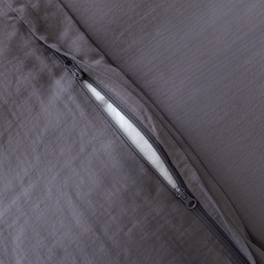 Close-up of a concealed zipper opening on a dark stone gray quilt cover with matching zipper hardware.