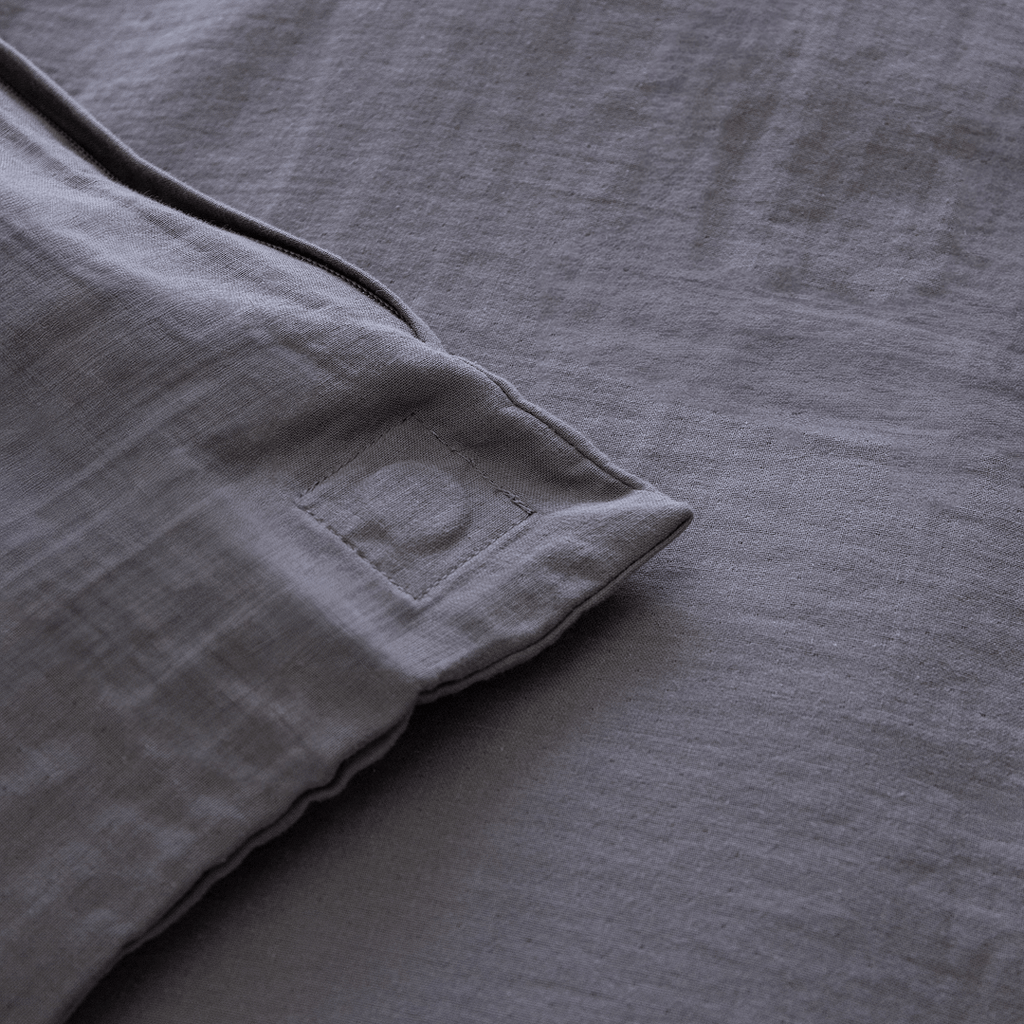 Close-up of the corner of a dark stone gray quilt cover showing a stitched square detail and textured stonewashed fabric.