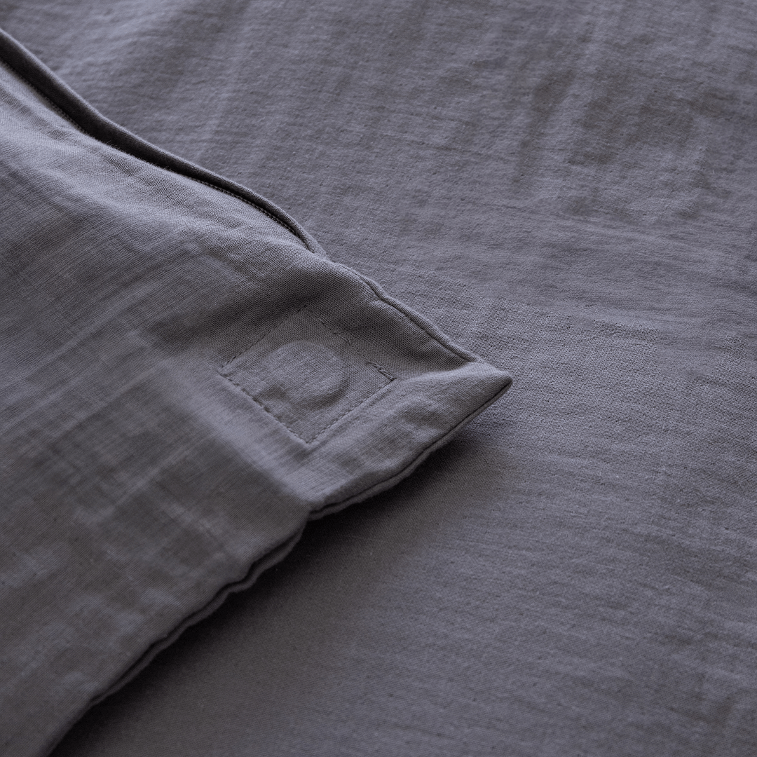 Close-up of the corner of a dark stone gray quilt cover showing a stitched square detail and textured stonewashed fabric.