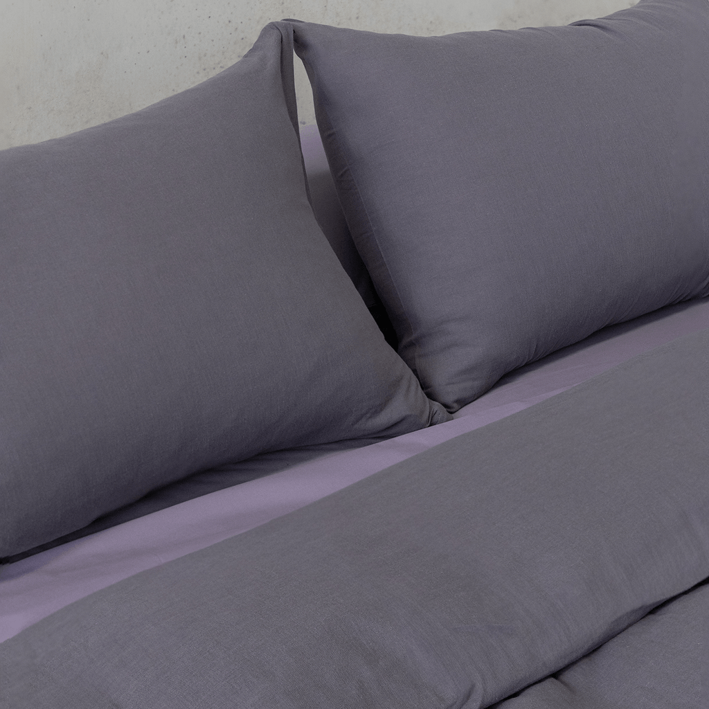 Close-up of two dark stone gray pillows resting against coordinating gray bedding.
