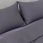 Close-up of two dark stone gray pillows resting against coordinating gray bedding.