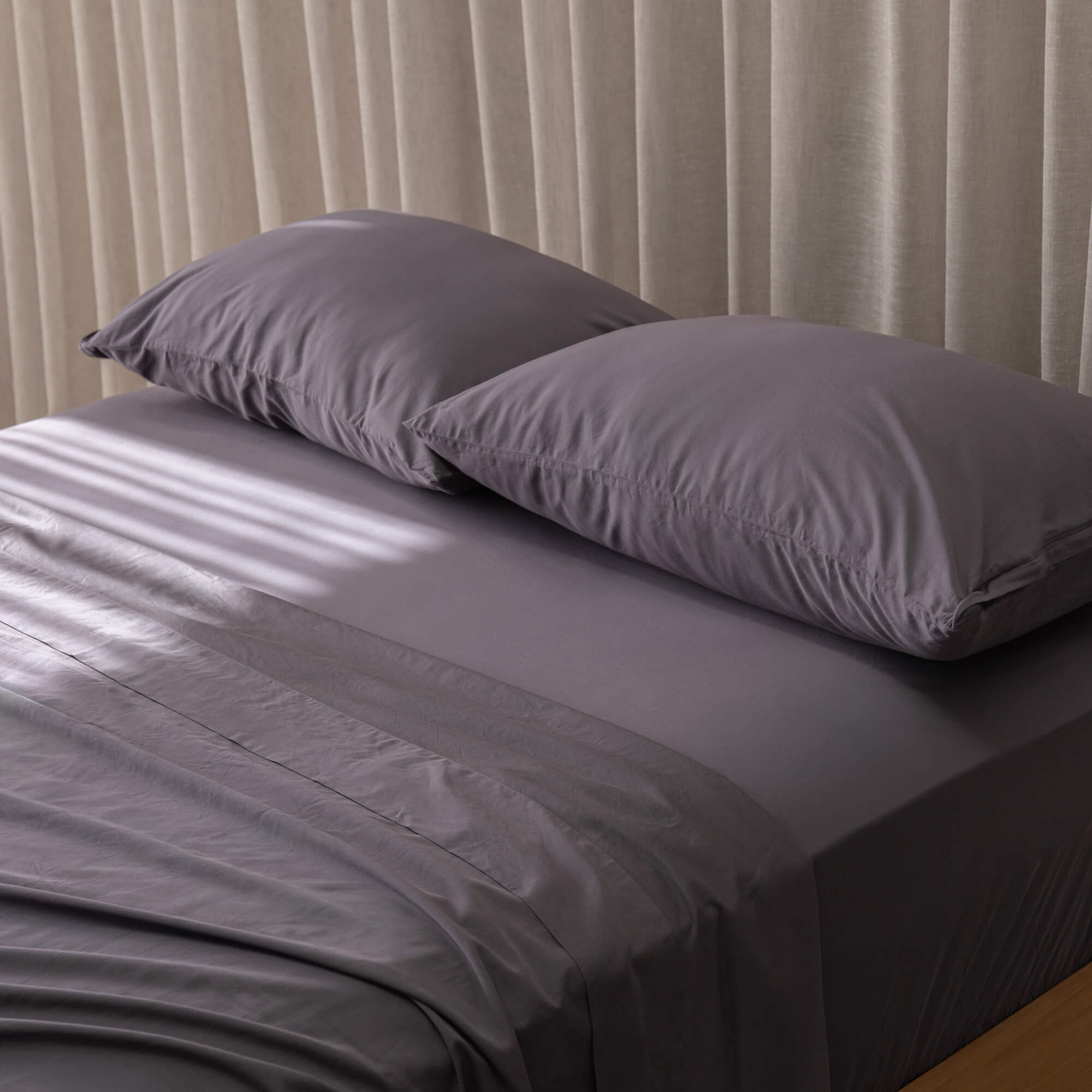 Close up of gray pillows and bedding with curtain background