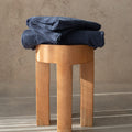 Wooden stool with folded blue towel on a neutral background.