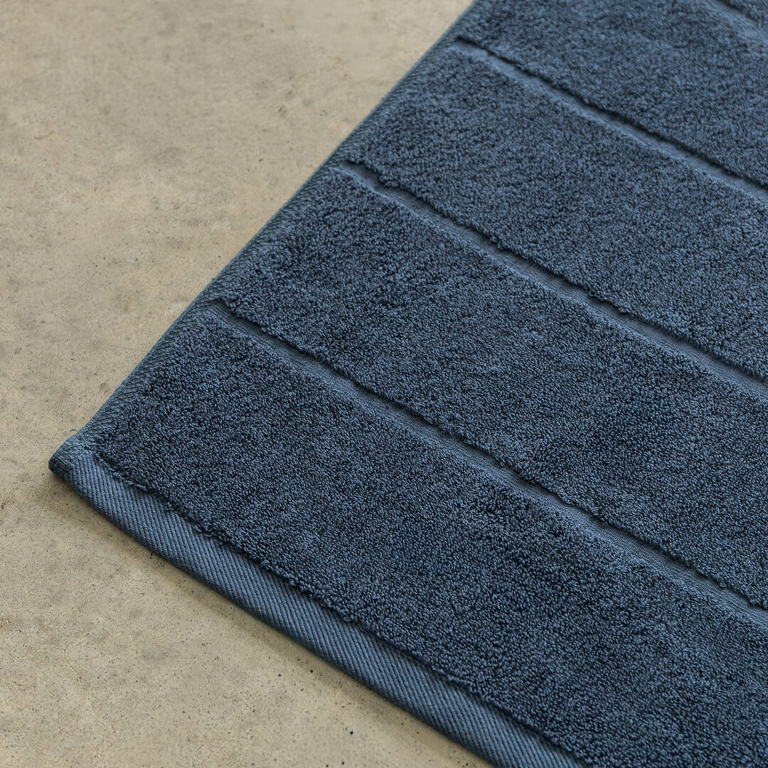 Close-up of a blue bath towel on a beige floor.