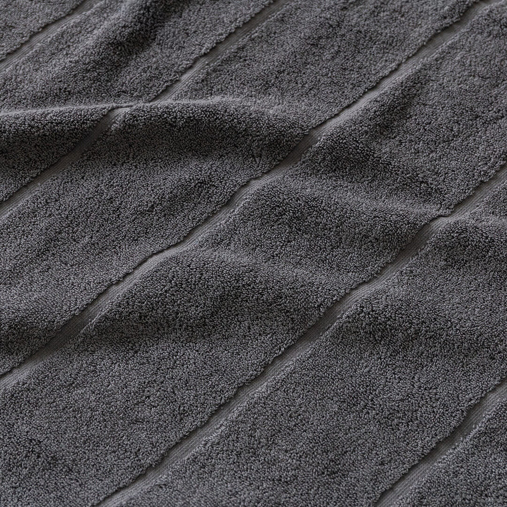 Close-up of textured charcoal grey bath towel fabric with diagonal lines.