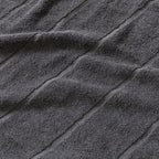 Close-up of textured charcoal grey bath towel fabric with diagonal lines.